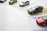 Kfz-Versicherungen vergleichen spart viel Geld Kleine Spielzeugautos stehen auf unterschiedlichen Geldscheinen