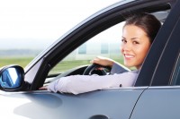 Business woman looking at camera through the car window. Junge Frau lächelt aus Autofenster
