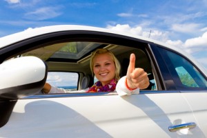 Autokredite sind so günstig wie nie Junge Frau freut sich über ihr Auto